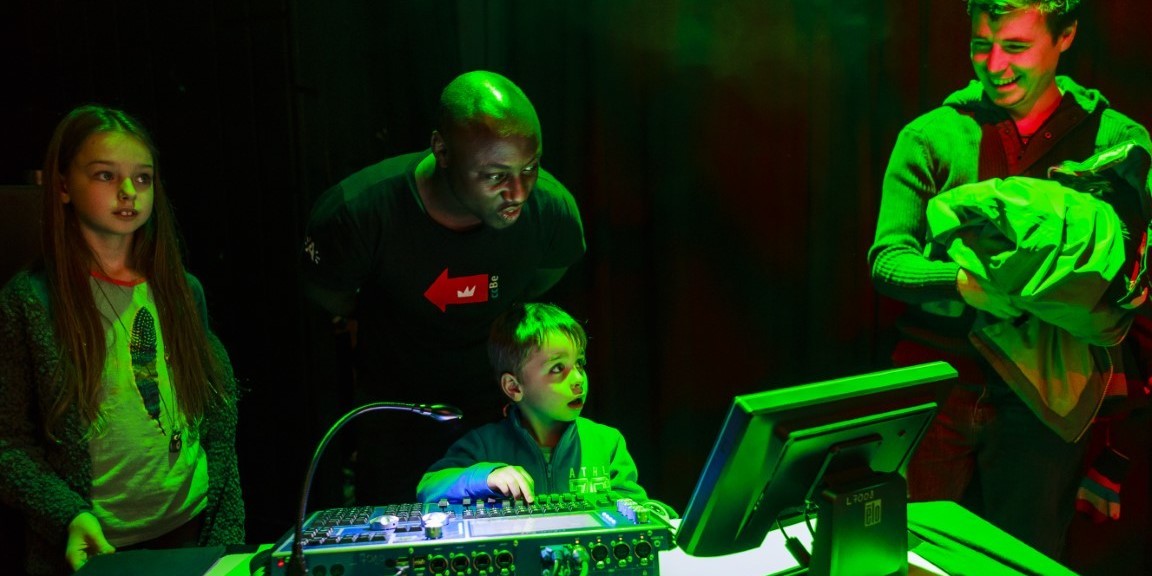 Technicus begeleidt kind om lichtshow te creëren in een cultuurcentrum Technicus begeleidt kind om lichtshow te creëren in een cultuurcentrum